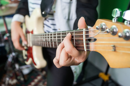 Midsection closeup of woman playing guitar in recording studio