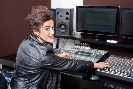 Portrait of confident young woman mixing audio in recording studio