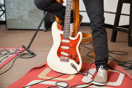 Low section of male performer with guitar in recording studio
