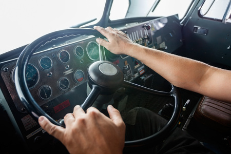 Cropped image of fireman's hands holding steering wheel of firetruck at stationの写真素材