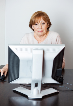 Senior woman using computer at desk in classの写真素材