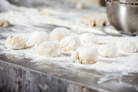 Closeup of dough balls covered with flour on table in bakeryの写真素材