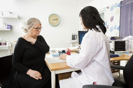 Female doctor explaining model to senior patient suffering from shoulder pain in clinicの写真素材