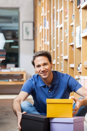 Portrait of smiling male customer with stacked cardboard boxes in shop