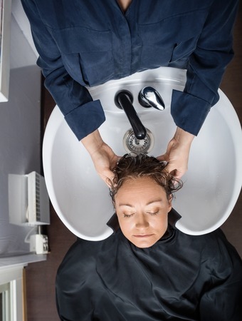 Directly above shot of mature woman getting hair washed in beauty salonの写真素材