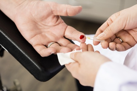 Cropped image of doctor taking blood sample of patient in clinicの写真素材