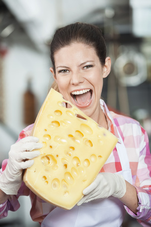Portrait of young saleswoman biting cheese in store