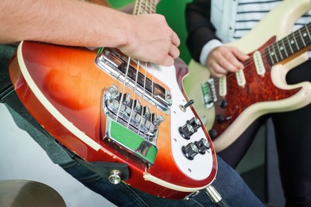 Midsection of band members playing guitars in recording studioの写真素材
