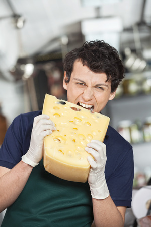 Portrait of young salesman biting cheese in storeの写真素材