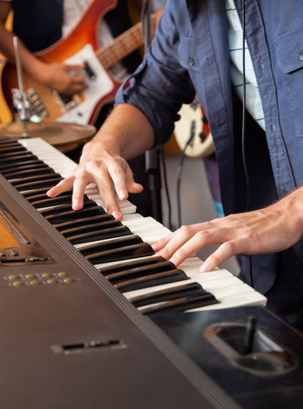 Midsection of male band member playing piano in recording studioの写真素材