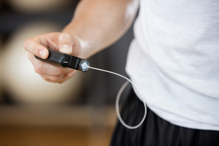 Midsection of young man using continuous glucose monitor in gym