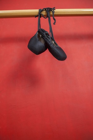 Ballet shoes hanging from handrail against red wall in studioの写真素材