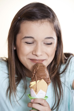 Smiling girl with eyes closed enjoying chocolate ice cream at parlorの写真素材