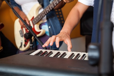 Closeup of man's hand playing piano in recording studioの写真素材