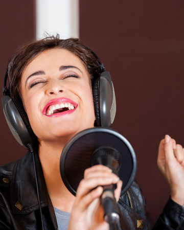 Young woman enjoying while singing in recording studioの写真素材