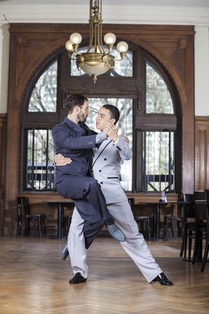 Confident tango dancer lifting male partner in restaurantの写真素材
