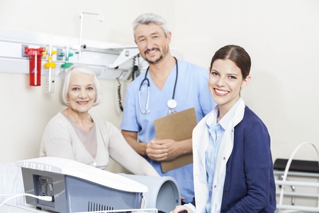 Portrait of smiling physiotherapists and female patient at rehab clinic