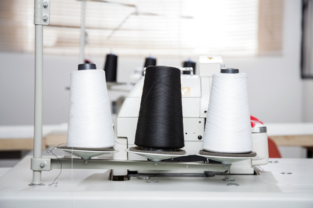 Black and white thread spools on workbench at sewing factoryの写真素材