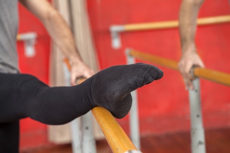 Cropped image of male trainer with leg on barre at dance studioの写真素材