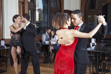 Male and female dancers doing tango while couple dating in restaurantの写真素材
