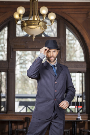 Mid adult man holding hat while performing tango in cafeの写真素材