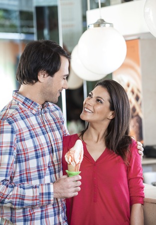 Happy mid adult couple with vanilla ice cream looking at each other in parlorの写真素材