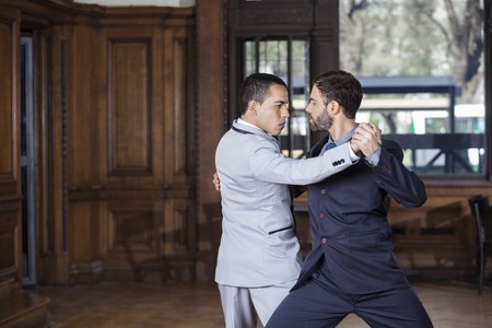 Male dancers performing Argentine tango together in restaurantの写真素材