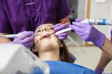 Closeup of young female patient being examined by dentists in clinicの写真素材