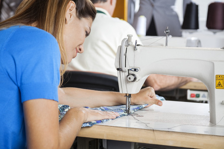 Rear view of female tailor using sewing machine at factoryの写真素材