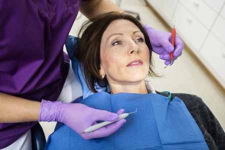 High angle view of dentist examining patient with tools in clinicの写真素材