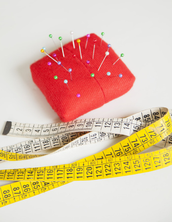 High angle view of pincushion and measure tape on table at sewing factoryの写真素材