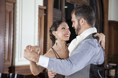 Side view of happy mid adult man and woman performing tango in restaurantの写真素材
