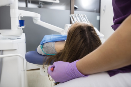 Cropped image of female dentist examining young patient in clinicの写真素材