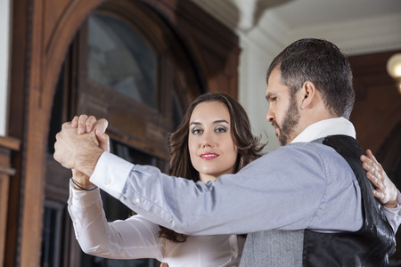 Low angle portrait of female tango dancer performing gentle embrace step with man in restaurant