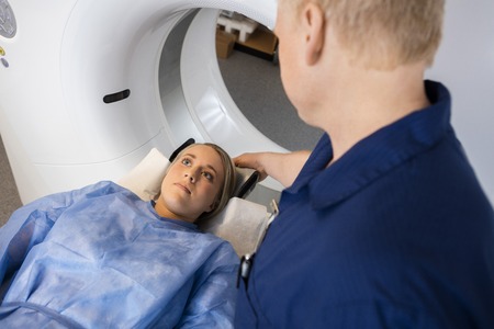 High angle view of male radiologist preparing female patient for MRI scan in hospitalの写真素材