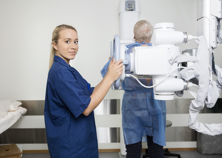 Portrait of confident female professional in uniform taking xray of patient in hospitalの写真素材