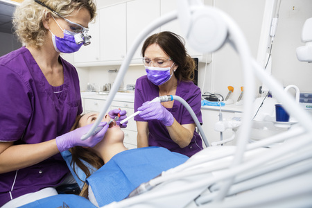 Mature female dentists working on young patient's teeth in clinicの写真素材