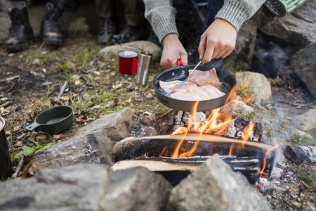 Man Cooking Meat Over Bonfire At Campsiteの写真素材