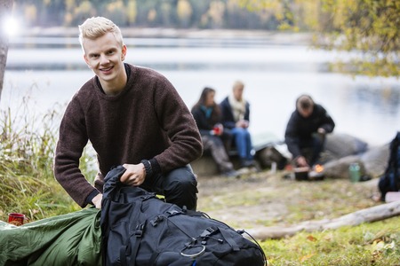 Young Man Unpacking Backpack At Campsiteの写真素材