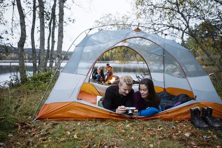 Couple Checking Photos Into Camera While Lying In Tentの写真素材