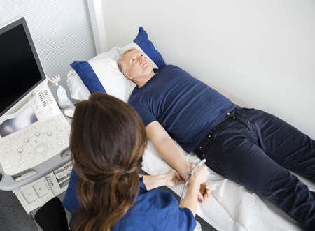 Doctor Using Ultrasound Probe On Males Wrist In Hospitalの写真素材