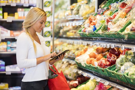 Woman Using Tablet Computer In Grocery Storeの写真素材