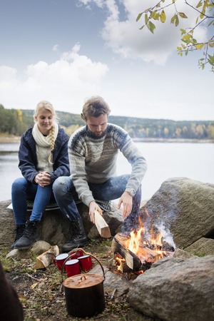 Couple Preparing Bonfire During Lakeside Campingの写真素材
