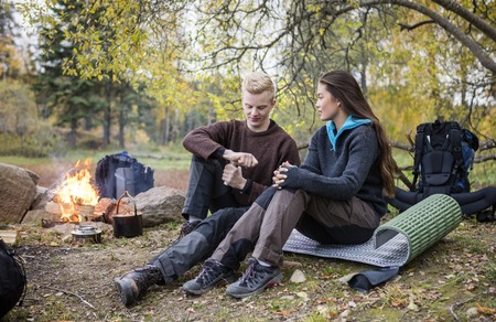 Woman Looking At Man Grinding Coffee During Camping In Forestの写真素材