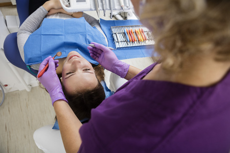 Dentist Holding Tools While Examining Young Patientの写真素材