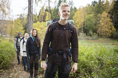 Smiling Man With Friends Hiking On Forest Trailの写真素材
