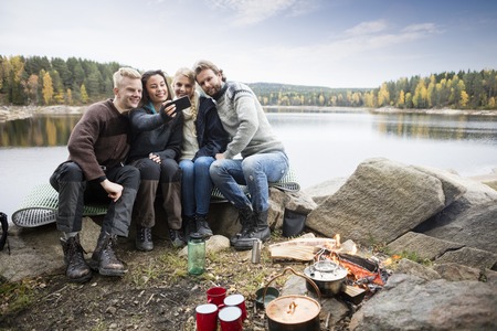 Friends Taking Self Portrait At Lakeside Campingの写真素材