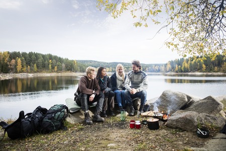 Friends Sitting On Lakeshore During Campingの写真素材