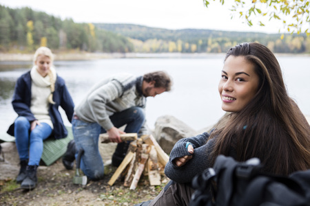 Woman With Friends Preparing Bonfire On Lakeside Campingの写真素材
