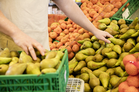 Midsection Of Salesman Arranging Fresh Pearsの写真素材